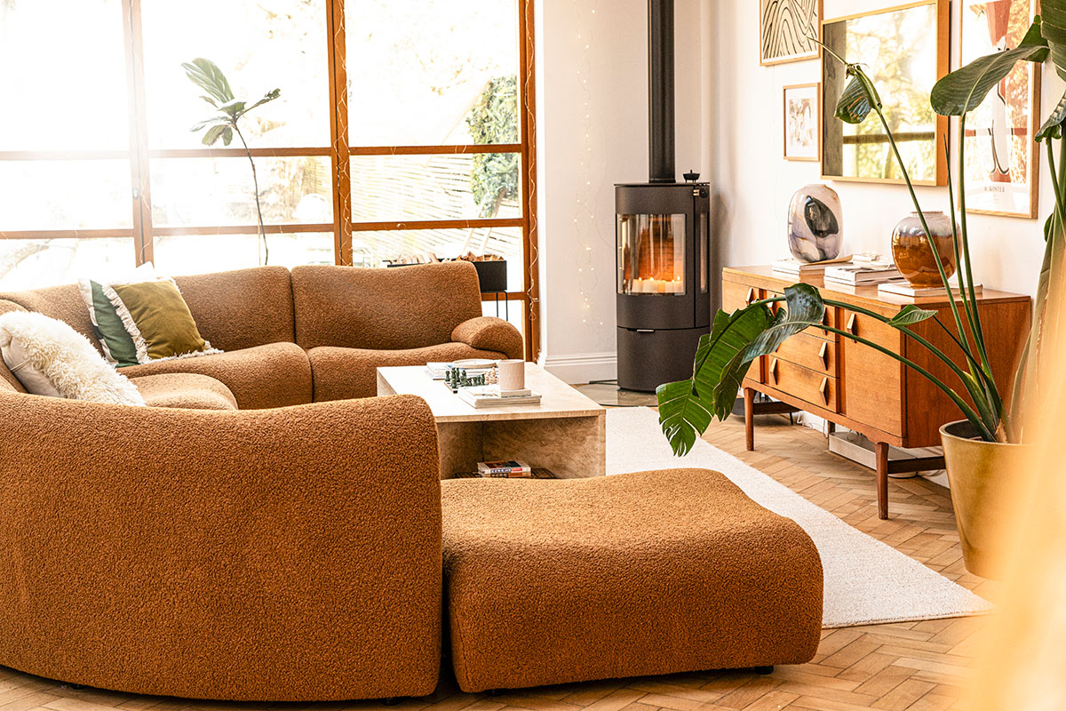 A warm and inviting living space featuring a curved bouclé sofa, soft neutral caramel tones and natural light.
