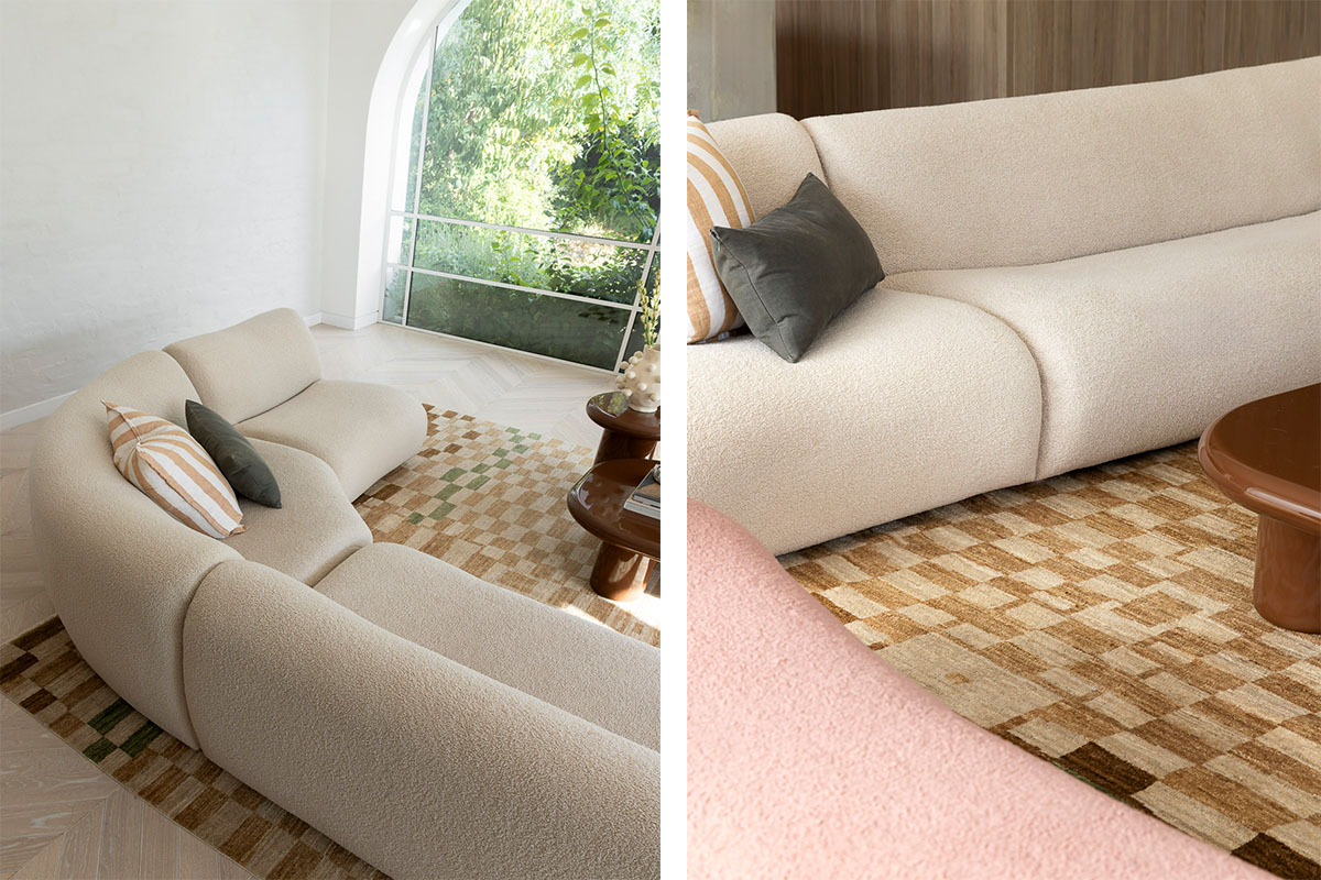 A serene living space featuring a curved sand-toned bouclé sofa and checkered rug framed by an arched window with lush greenery outside.